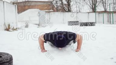 强壮的男人在雪地上做俯卧撑，交叉锻炼